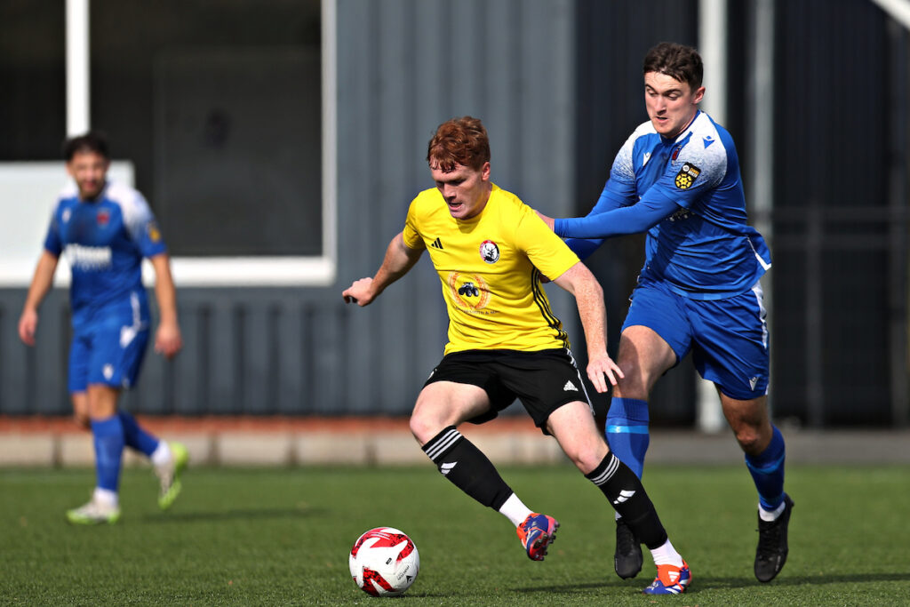 Buckley's Nick Grogan is pressured by Ruthin's Sam Jones during Ruthin Town vs Buckley Town in Round 10 of the JD Cymru North at Maes Tegid, Bala