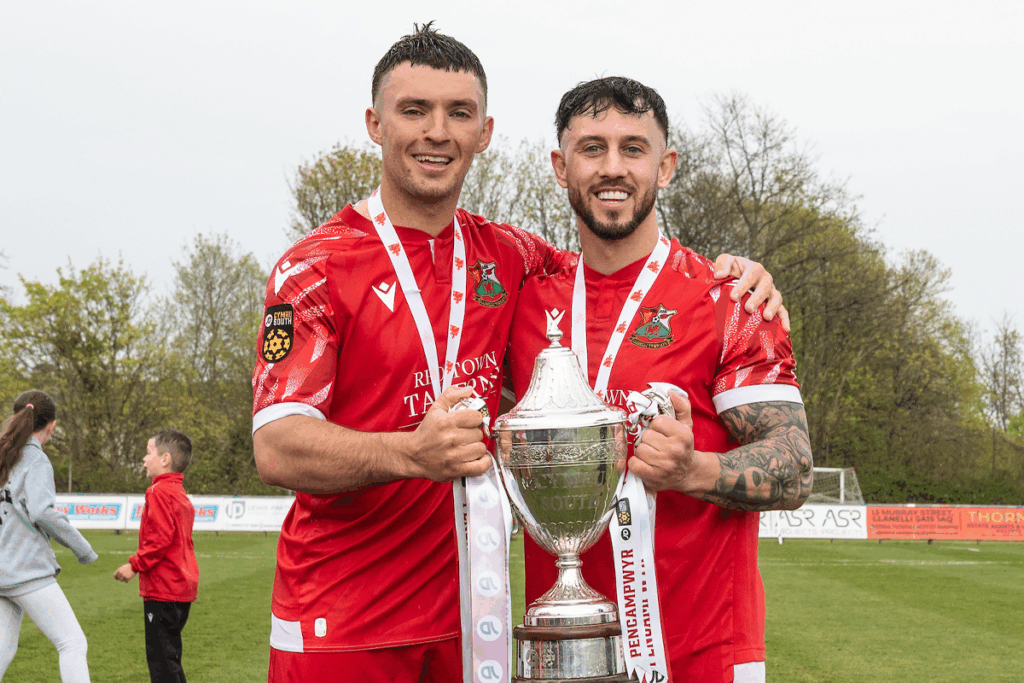 Liam Eason (L) and Cam Strinati (R) holding the JD Cymru South title in a Llanelli Town strip