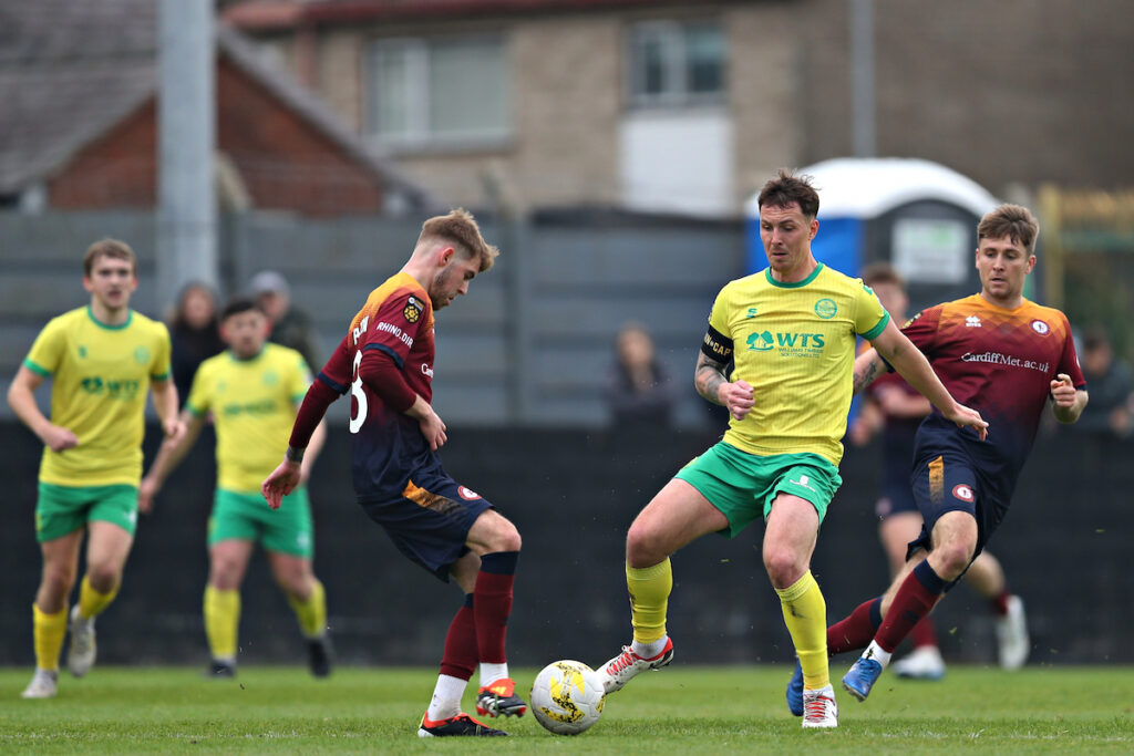 Ryan Sears of Caernarfon pressures Cardiff Met's Daniel Barton during Caernarfon Town vs Cardiff Metropolitan University FC in Round 32 of the JD Cymru Premier at The Oval, Caernarfon