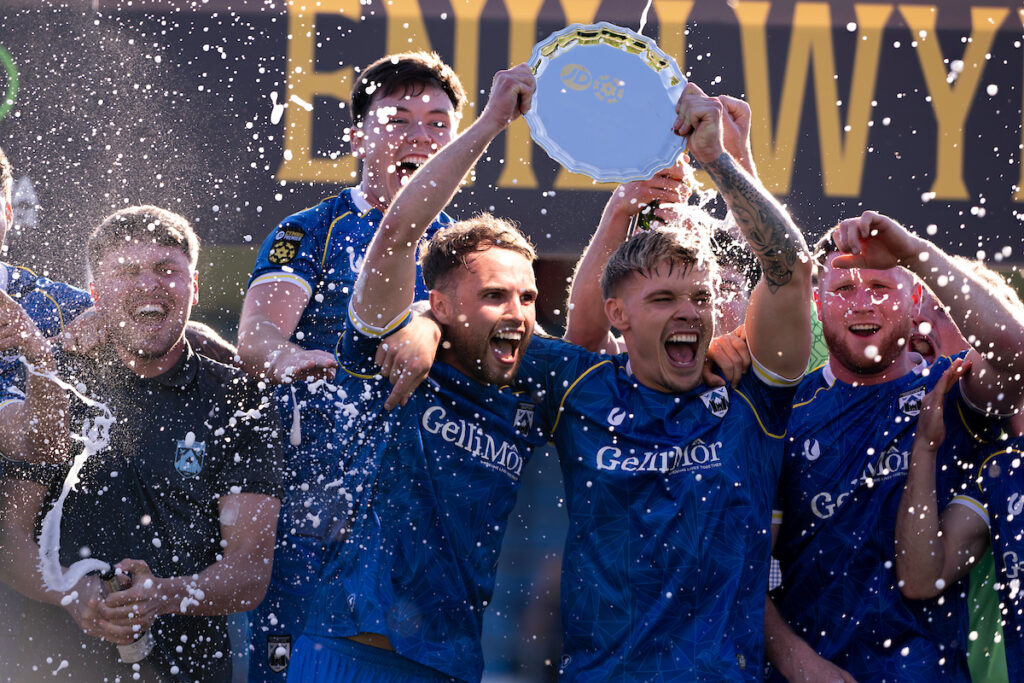 Haverfordwest County's Dylan Rees and Haverfordwest County's Corey Shephard lift the trophy during the JD Cymru Premier 24/25 - European Play Off match between Haverfordwest County AFC and Caernarfon Town at Ogi Bridge Meadow Stadium in Haverfordwest on the 18th May 2025